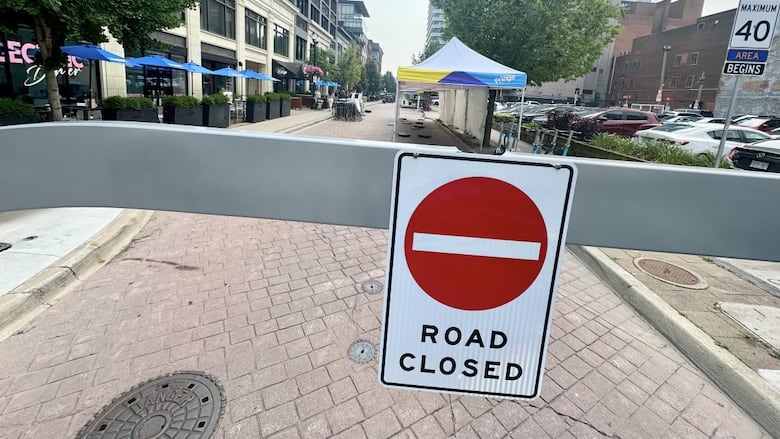 a road closed sign with tents in the background