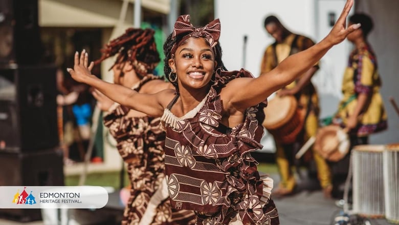 Woman in brown dress and bow headband with her arms raised smiling