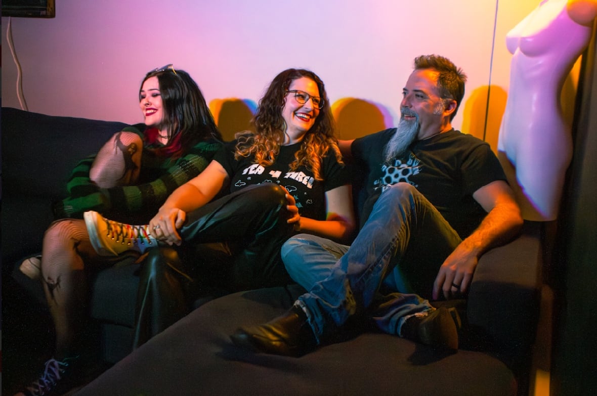 Three people sitting on a couch smiling and laughing.
