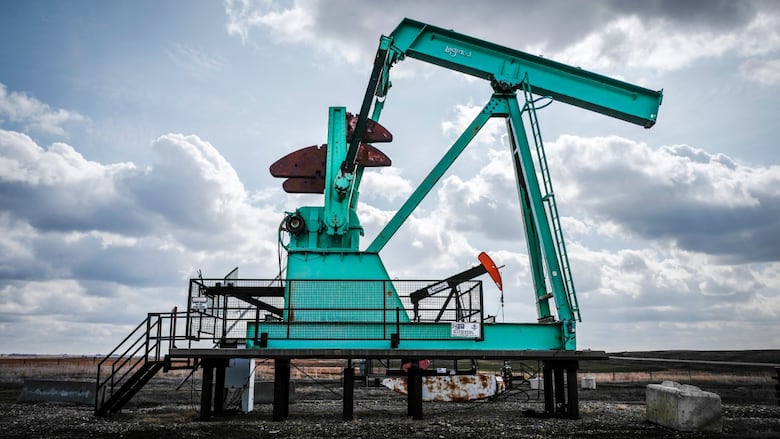 A de-commissioned pumpjack is pictured beside a functioning one.