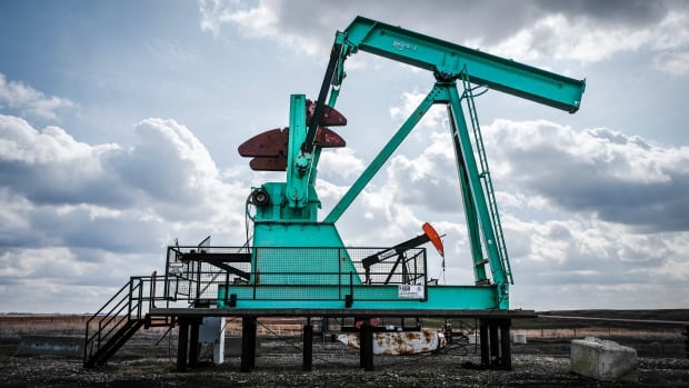 A de-commissioned pumpjack is pictured beside a functioning one.