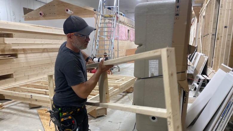 A man carries a door frames in a factory that builds modular homes.