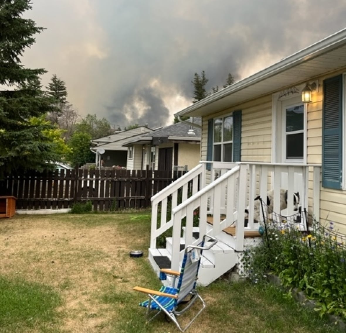 A house is pictured with wildfire smoke filling the air in the background.