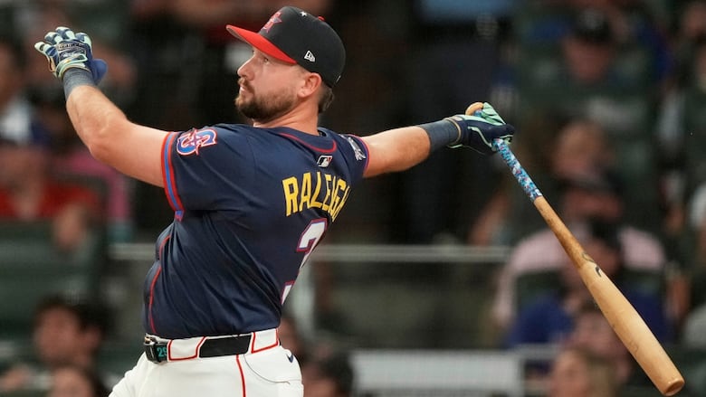 A men's baseball player is shown on the follow through of a swing of the bat.