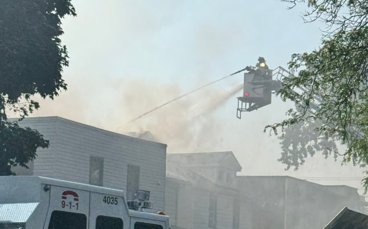 A firefighter in a bucket on the end of a ladder on a aerial fire fighting truck sprays water on a building on Campbell Ave. on July 14, 2025.