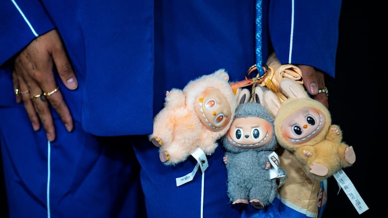 A man in a blue suit carries three demonic but cute toys on his person.