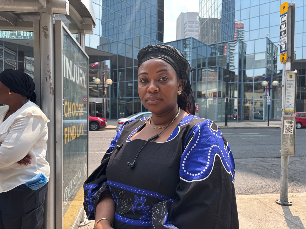 A woman with a serious expression looks to the camera
