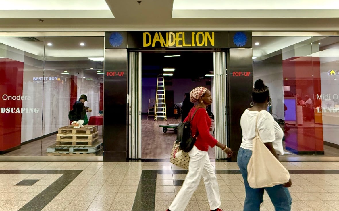 Two women walk by a mall storefront with the a sign that says "dandelion."