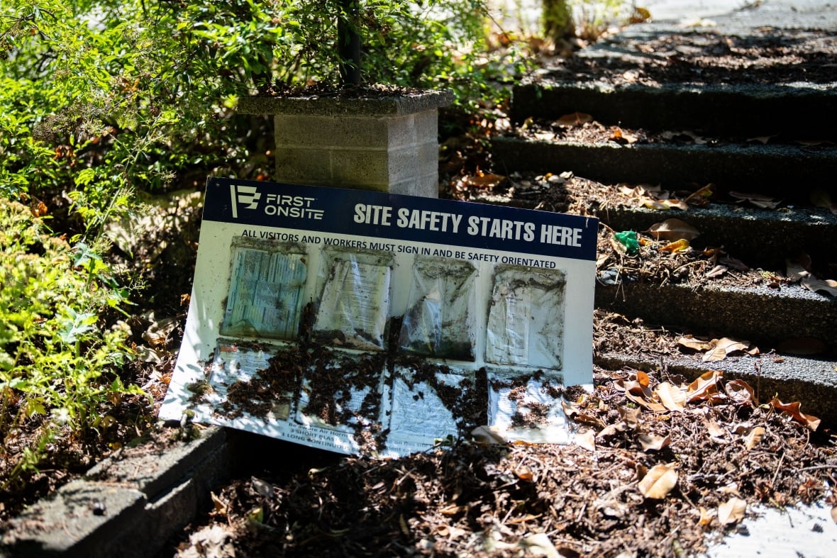 A construction sign lies amongst leaves on the steps outside of a home. It says, 'Site Safety Starts Here.'