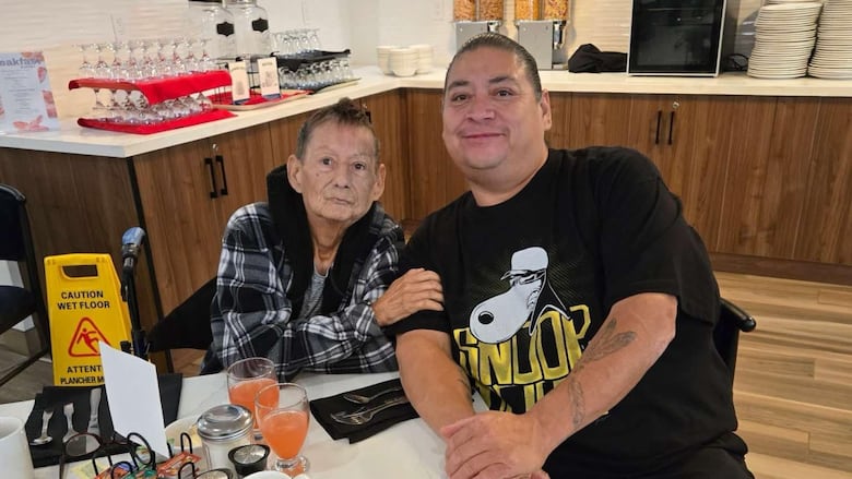 A woman and her adult son sit at a table