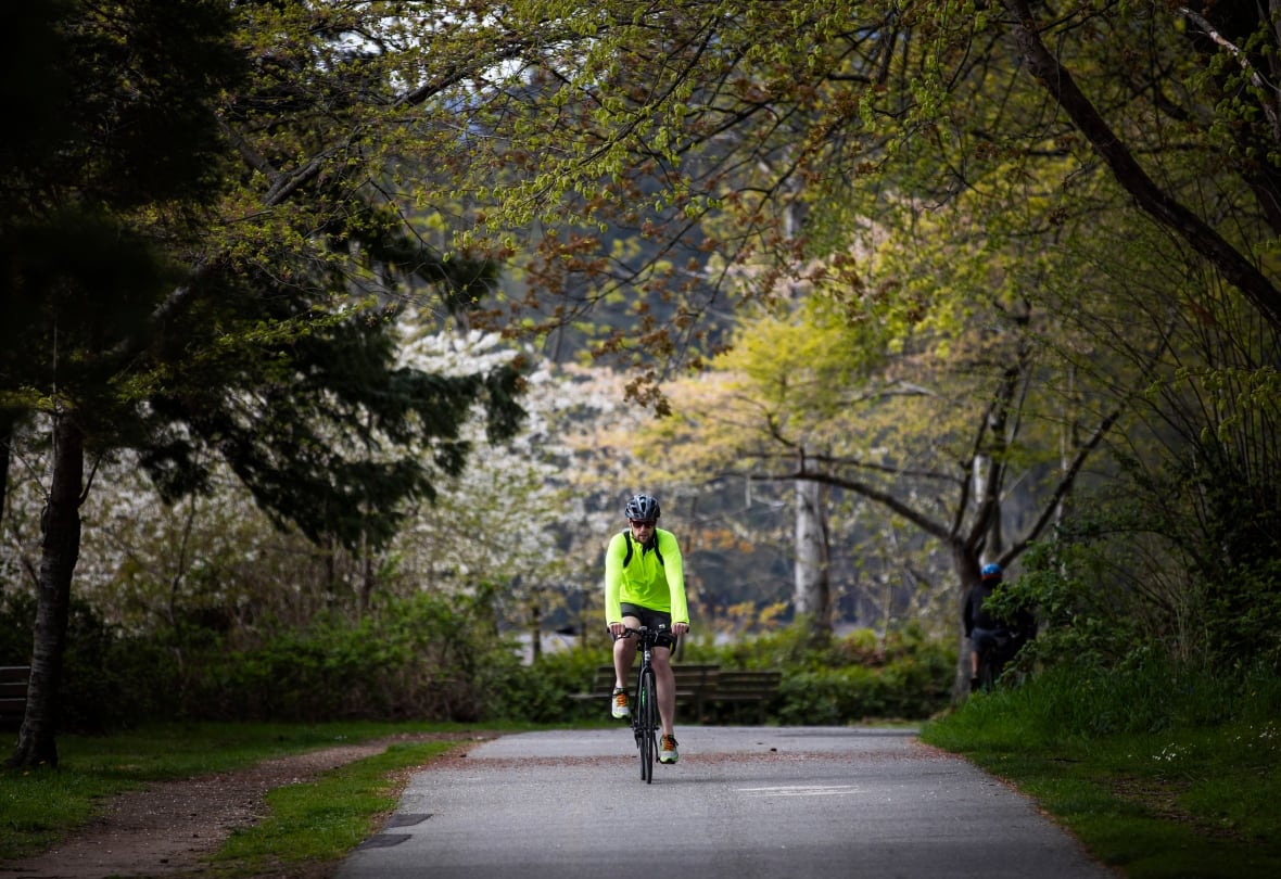 A man wearing a neon jacket and a helmet rides a bicycle.