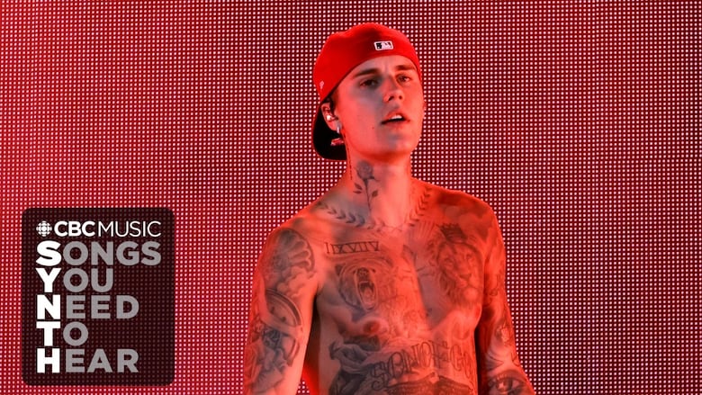Justin Bieber performs on stage in a red baseball cap work backwards. 