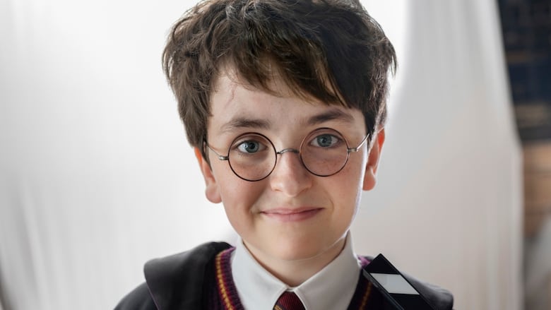 Young boy with brown hair and round wire glasses in a school uniform shirt and tie