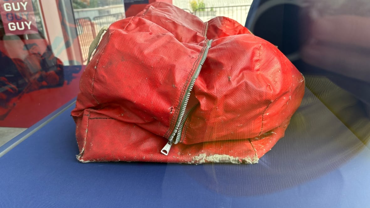 An old red hockey bag, small by comparison to modern day hockey bags.