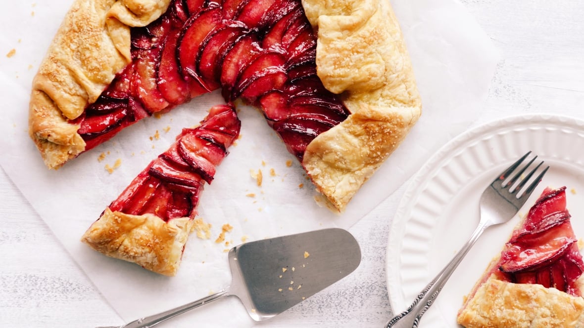 Top down shot of a plum galette with a slice of it on a plate. 