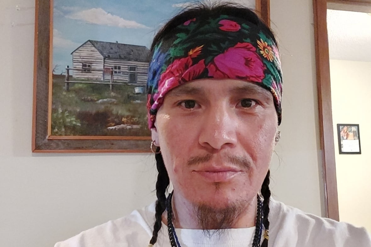 An Indigenous man with braids poses for a photo.