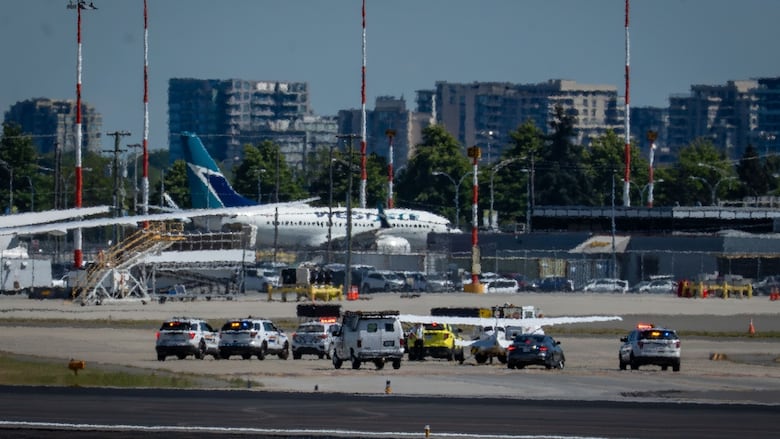 A plane sits on the runway surrounded by police vehicles.