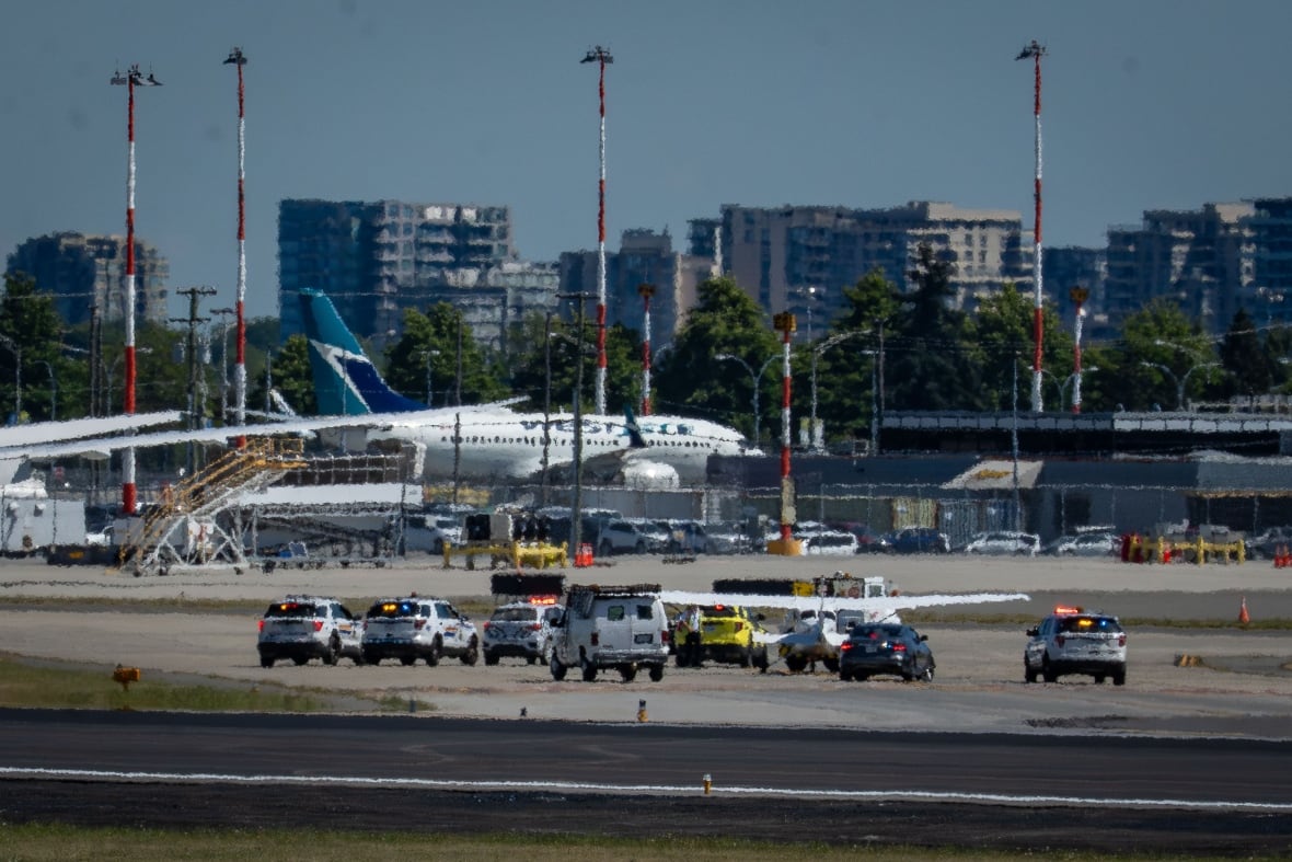 A plane sits on the runway surrounded by police vehicles.