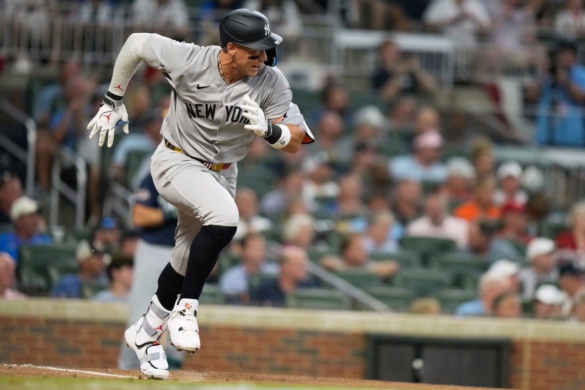 Baseball player in grey uniform with New York across the chest running towards a base.