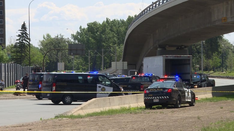 A cube van with the back open sits on a Calgary road surrounded by police vehicles.