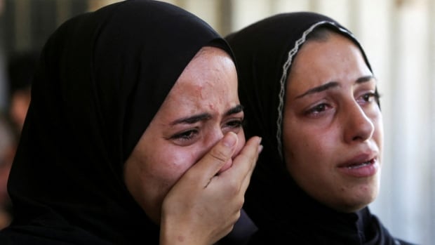 Two women in religious headcovering have anguished looks on their faces in a closeup photo.