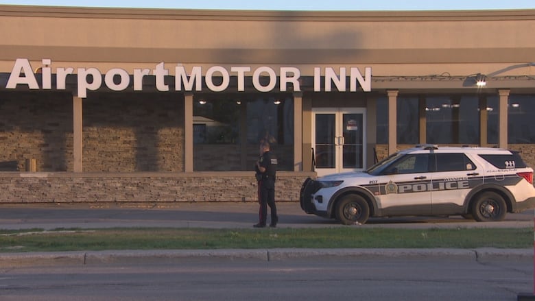 A police officer and police car are outside of a hotel