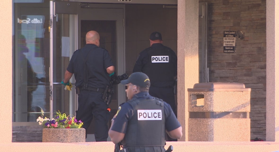 Three police officers are seen at the front door of a hotel.