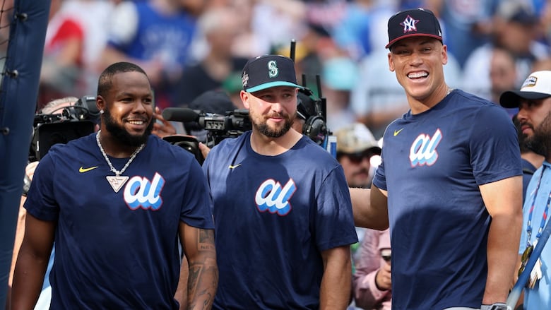 Three men's baseball players smile and pose for a photo.