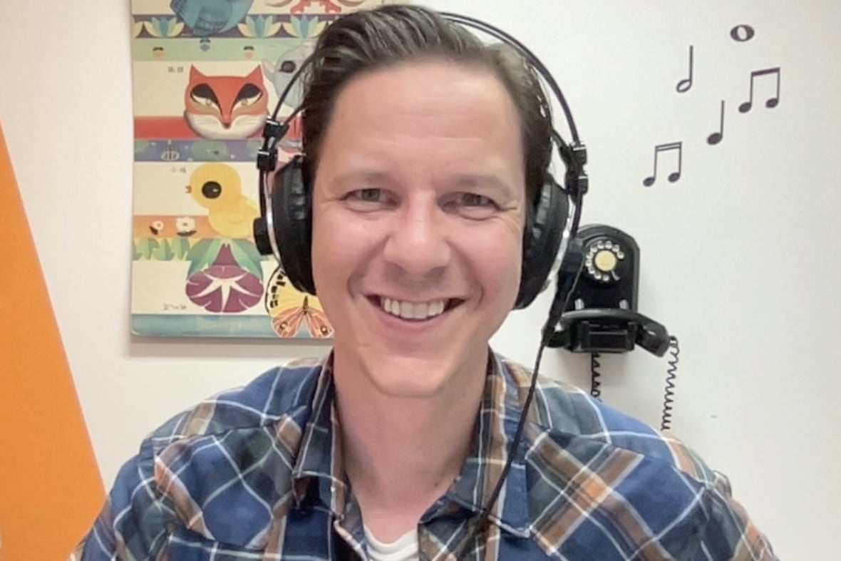 A man wearing headphones with a black phone in the background.