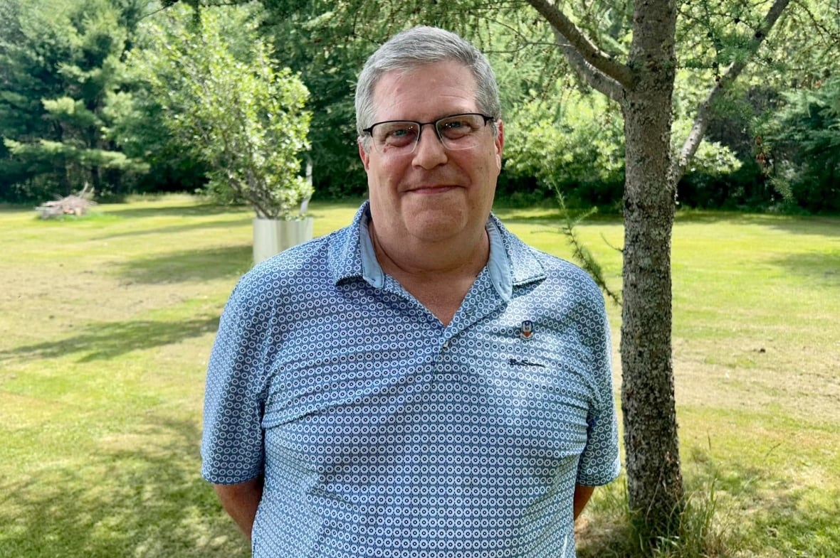 Um homem em uma camisa azul de golfe do lado de fora em um dia ensolarado.