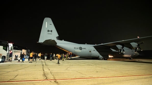 Dozens of people are seen walking into a large aircraft.