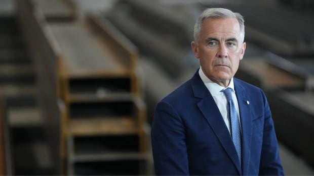 A man in a suit stands in a factory.