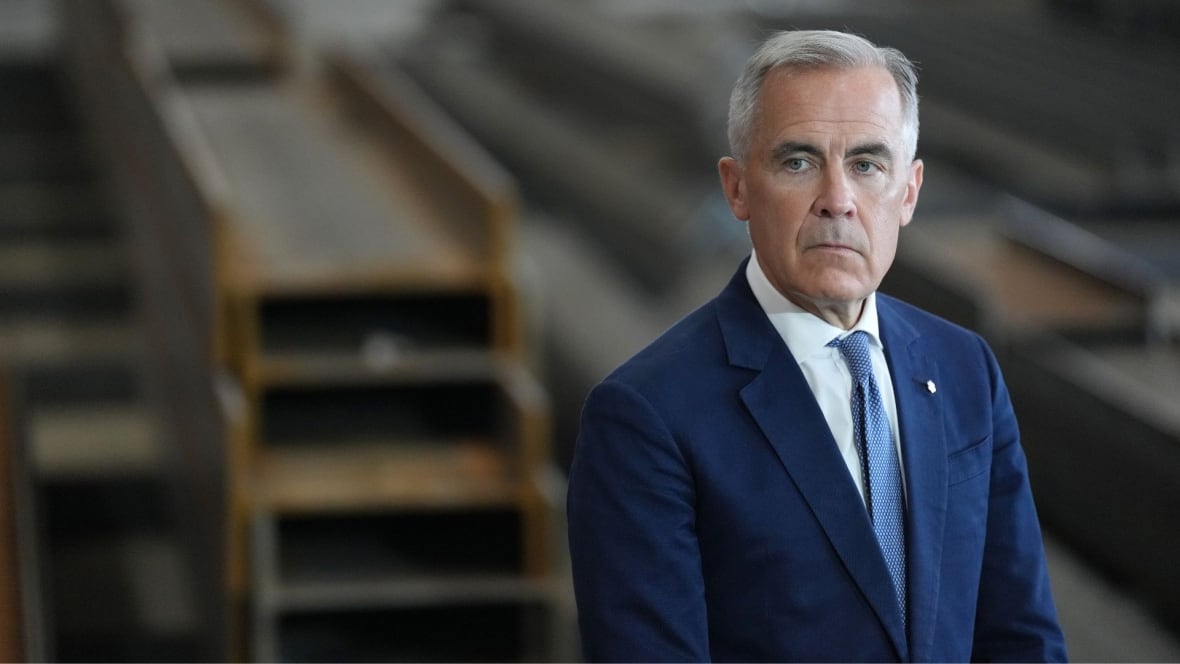 A man in a suit stands in a factory.