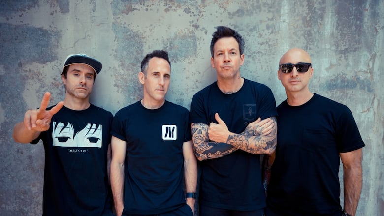 A group of men wearing black t shirts and pants smile at the camera while posing.