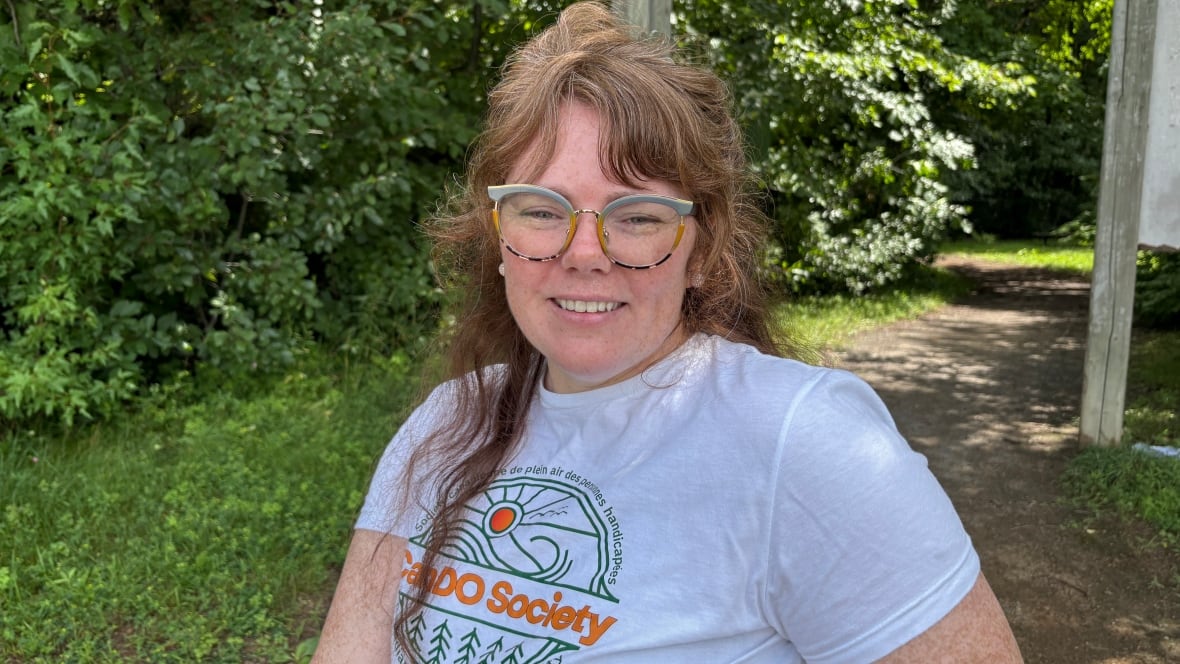 Woman poses in front of a nature trail.