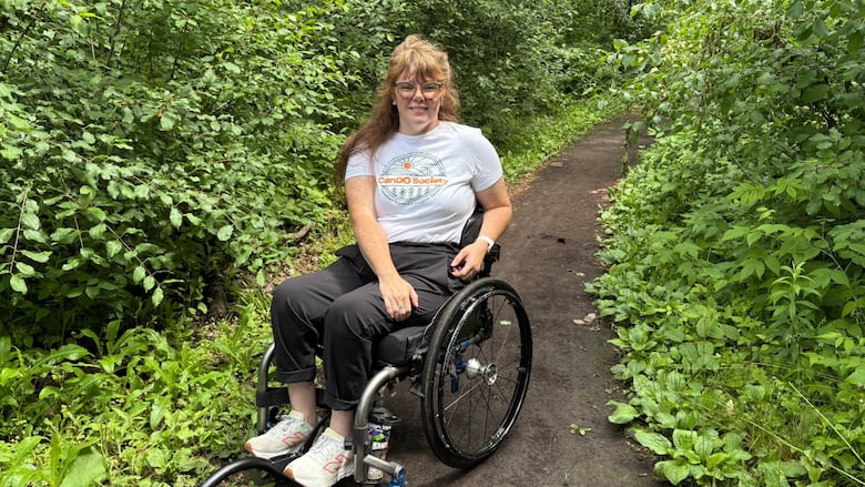 A woman in a wheelchair poses on an accessible hiking trail near the Nepean Sportsplex. 