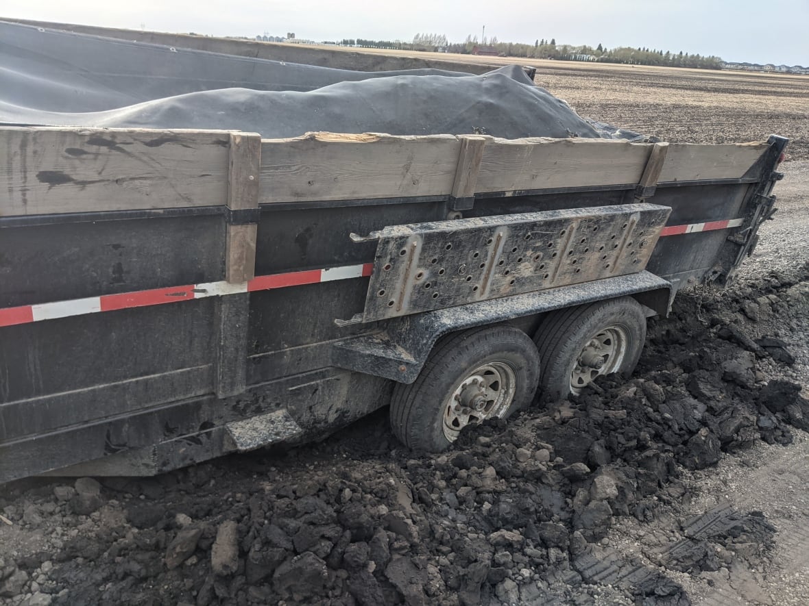 A trailer is stuck in a large groove in a dirt road near the Morris family farm.