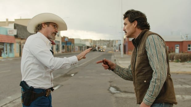 A man in a cowboy hat argues with a man in a vest. 