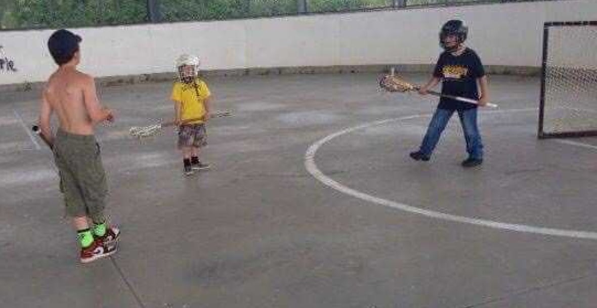 Three boys playing box lacrosse.