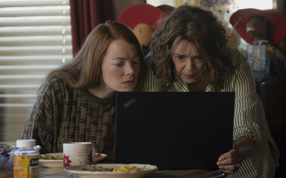 Two women look intently at a laptop screen.