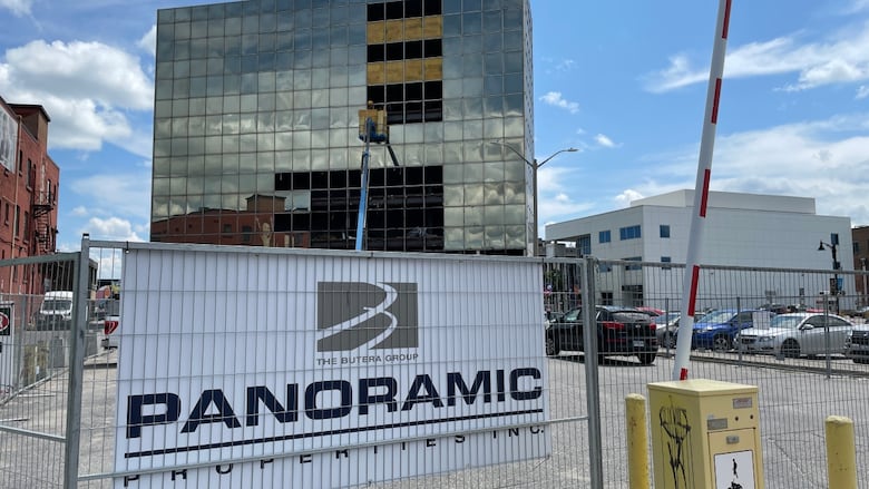 A fenced-off area with a sign that says Panoramic Properties and a large building in the background.