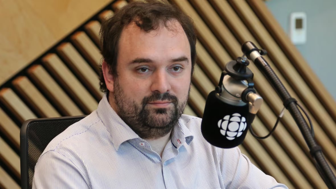 A man pictured sitting in front of a microphone