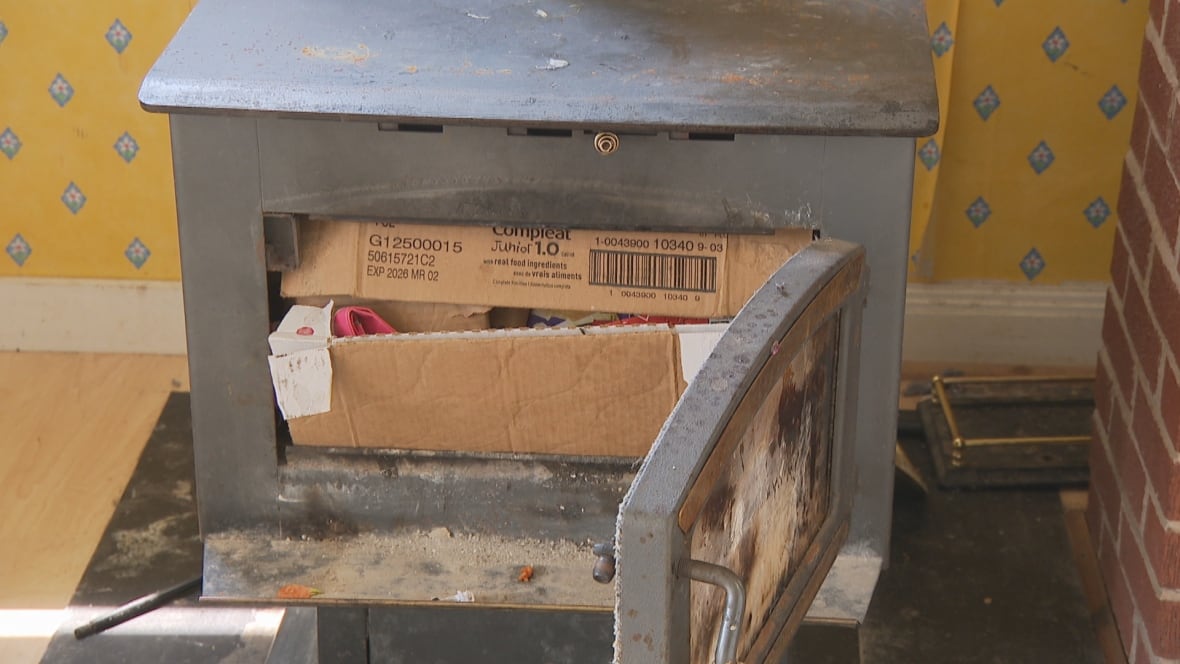 A small wood stove packed with dust and miscellaneous debris.