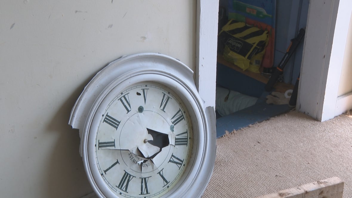 A broken analog clock sits on the floor of a home.