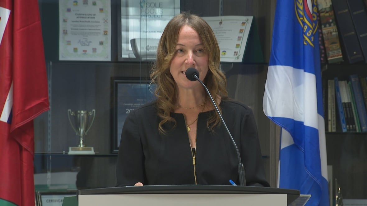 Nicole standing at the podium, looking down slightly and smiling slightly.