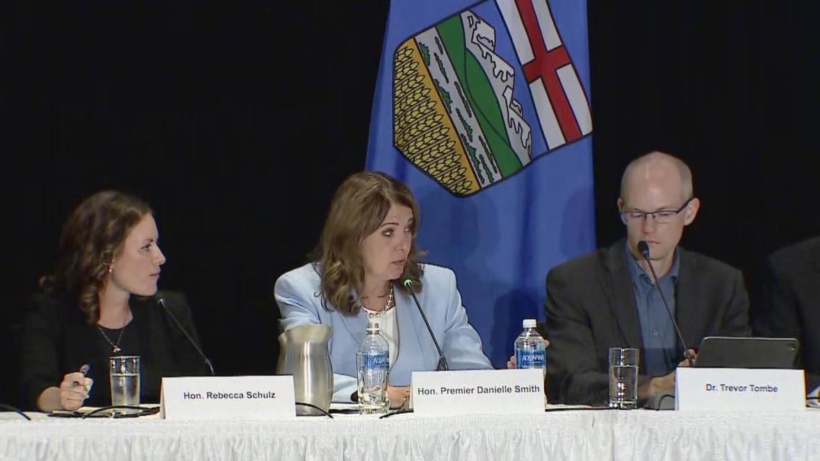 A seated woman speaks, flanked by a man and another woman.