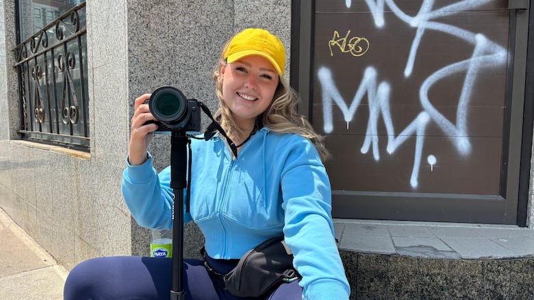 A woman holding a camera on a monopod smiling at the camera