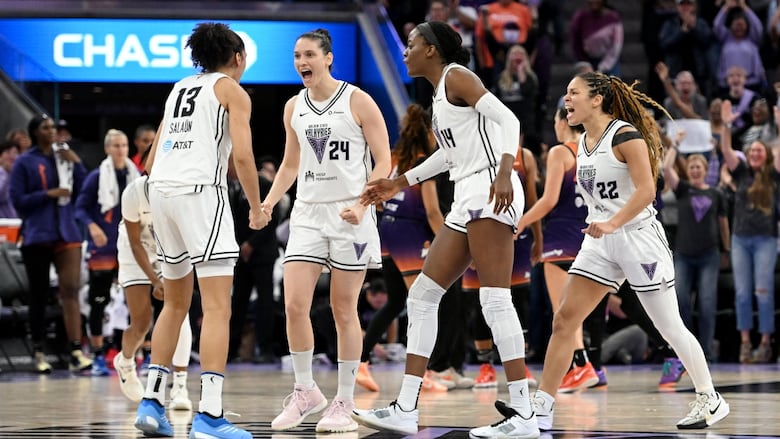 Women's basketball players celebrate after scoring during a game.