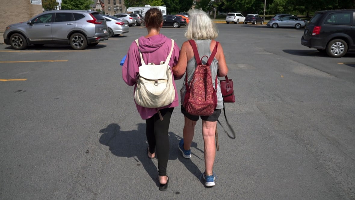 Two women walking through a parking lot.