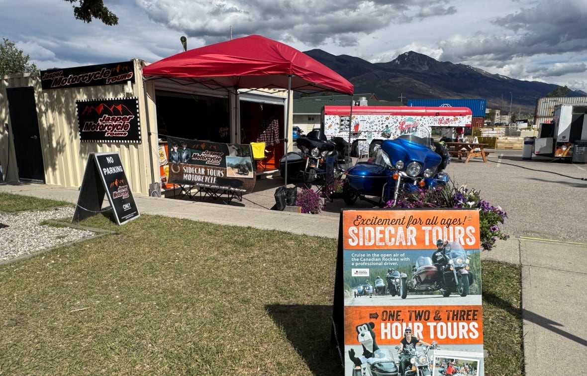 A sign displayed in front of a seacan retail kiosk at a pop-up business village in Jasper, advertises motorcycle tours. 
